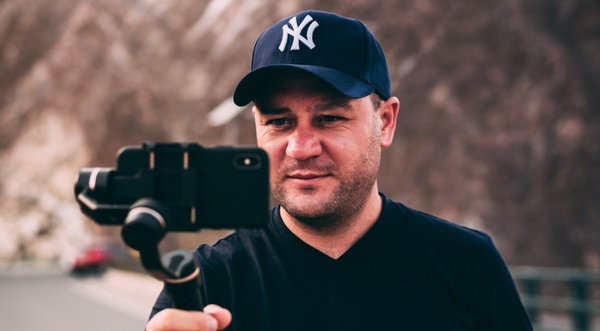 Man in a Yankees baseball cap taking a photo. 