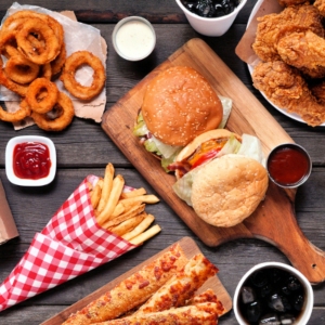 Table of pore-clogging junk food including cheese burgers, onion rings, fries, and other greasy foods.