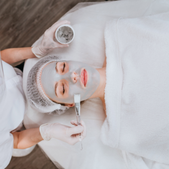 Esthetician applies a face mask to client