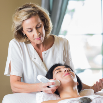 Esthetician cleansing client's skin