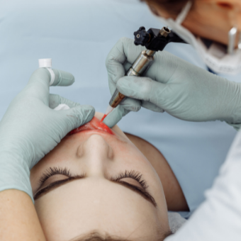 woman tattoos client's lips