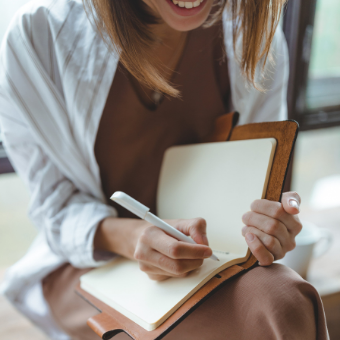 smiling woman writes in her journal